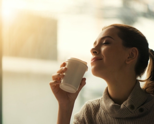 smiling-woman-drinking-coffee-with-eyes-closed