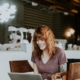 young-professional-female-smiling-at-computer-screen-in-cafe