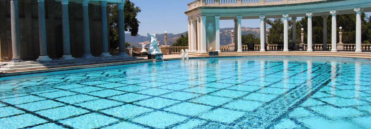 A crystal-blue pool on a sunny day at Greco-Roman-looking spa.