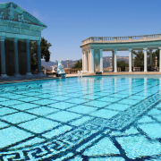 A crystal-blue pool on a sunny day at Greco-Roman-looking spa.