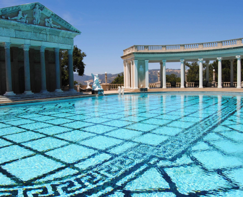 A crystal-blue pool on a sunny day at Greco-Roman-looking spa.
