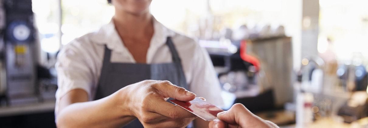 Cashier Accepts Card Payment From Customer In Delicatessen
