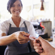 Cashier Accepts Card Payment From Customer In Delicatessen