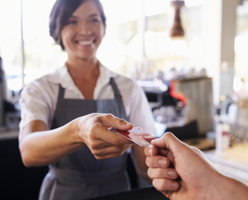 Cashier Accepts Card Payment From Customer In Delicatessen